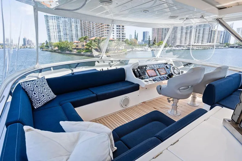 Sea Zar Yacht Photos Pics Luxurious 2019 Sunseeker 86 Yacht interior with blue seating and modern helm, overlooking waterfront cityscape.