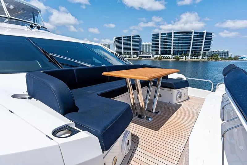 Sea Zar Yacht Photos Pics Luxurious 2019 Sunseeker 86 Yacht deck with seating and table, overlooking waterfront buildings.