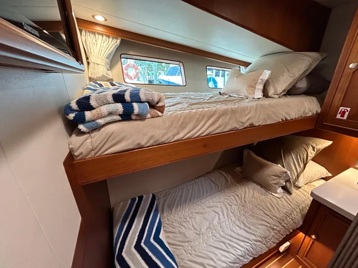 Novia II Yacht Photos Pics Bunk beds in a 2020 Marlow 66E yacht cabin with cozy bedding and striped blankets.