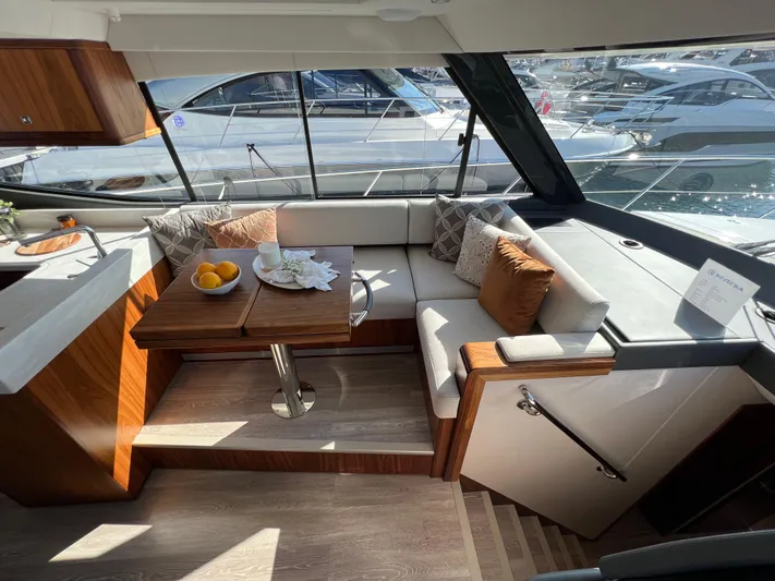 Scorpius Yacht Photos Pics Luxurious interior of 2022 Riviera 505 SUV yacht with elegant seating and table.