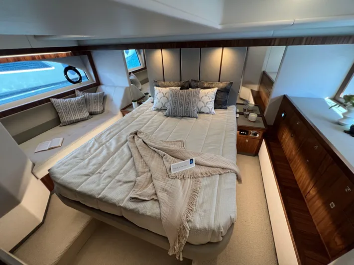 Scorpius Yacht Photos Pics Luxurious bedroom interior of 2022 Riviera 505 SUV yacht with elegant bedding and wood accents.