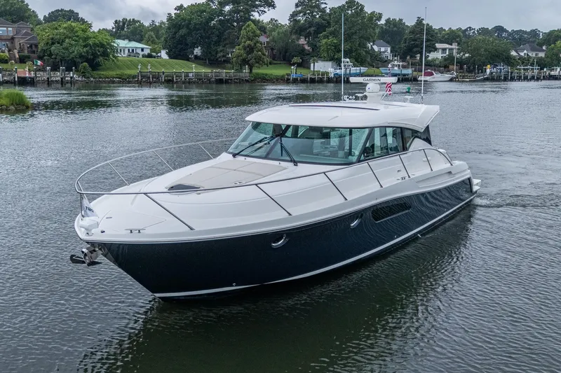  Yacht Photos Pics 2020 Tiara Yachts C44 Coupe cruising on a serene waterway.