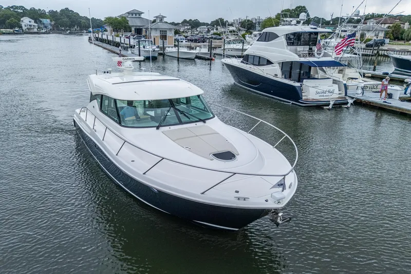  Yacht Photos Pics 2020 Tiara Yachts C44 Coupe cruising in a marina, surrounded by other boats.