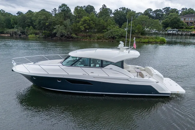  Yacht Photos Pics 2020 Tiara Yachts C44 Coupe cruising on a serene river with lush greenery.