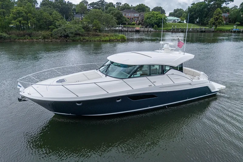  Yacht Photos Pics 2020 Tiara Yachts C44 Coupe cruising on a serene river with lush greenery.