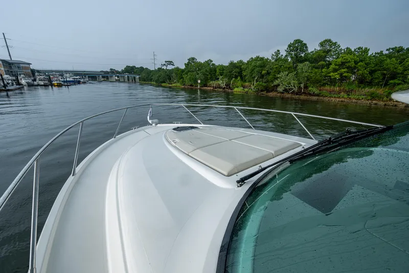  Yacht Photos Pics 2020 Tiara Yachts C44 Coupe cruising on a serene river near lush greenery.