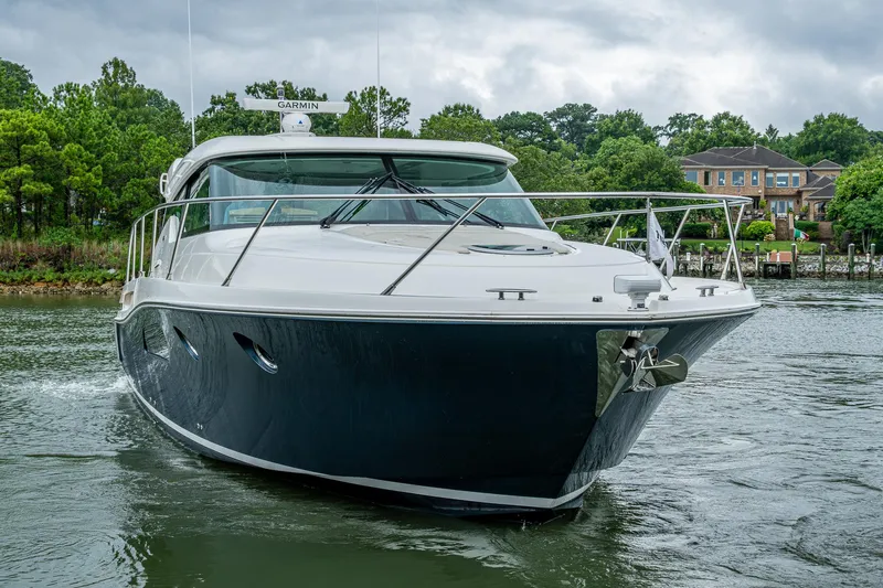 Yacht Photos Pics 2020 Tiara Yachts C44 Coupe cruising on a serene waterway with lush greenery.