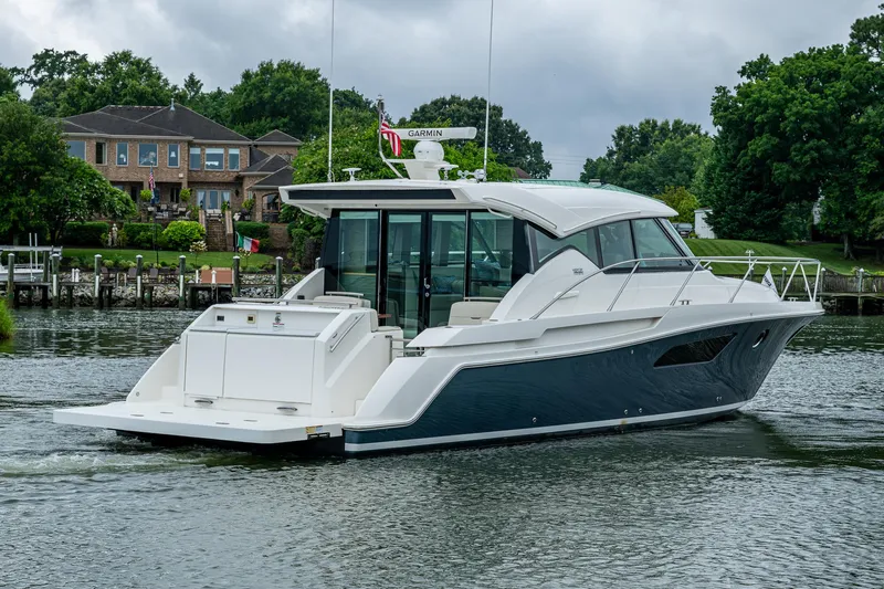  Yacht Photos Pics 2020 Tiara Yachts C44 Coupe cruising on a serene waterway near luxury homes.