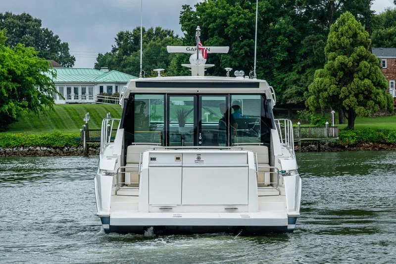  Yacht Photos Pics 2020 Tiara Yachts C44 Coupe on water, rear view with lush greenery background.
