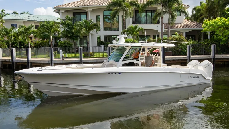 Double Nickel Yacht Photos Pics 2023 Boston Whaler 380 Outrage boat docked near a luxurious waterfront home.