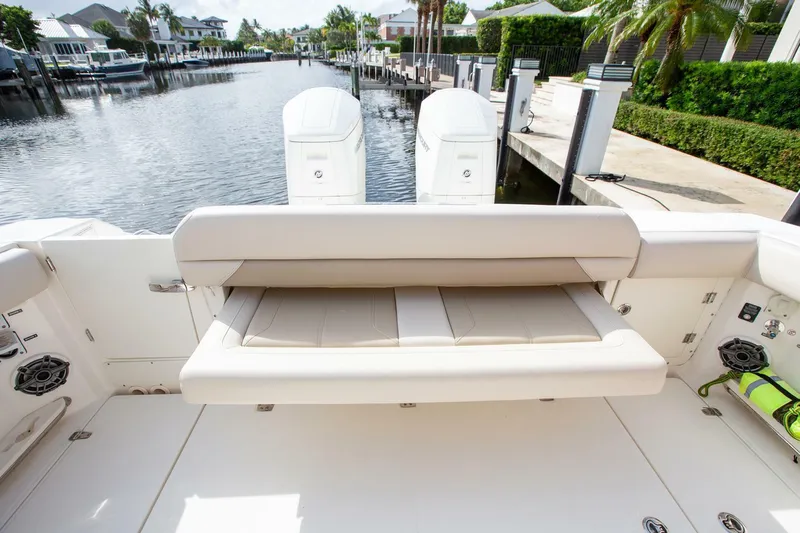 Double Nickel Yacht Photos Pics 2023 Boston Whaler 380 Outrage boat with foldable seating, docked in a serene canal setting.
