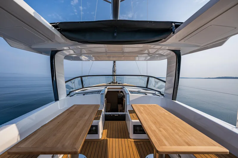 San-197 Yacht Photos Pics 2025 Hanse 460 yacht deck with wooden tables, overlooking calm sea and clear sky.