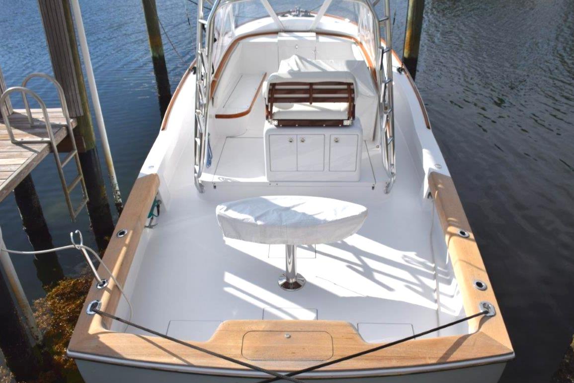 2024 L&H Walk-Around Sportfish boat docked, featuring spacious deck and seating area.
