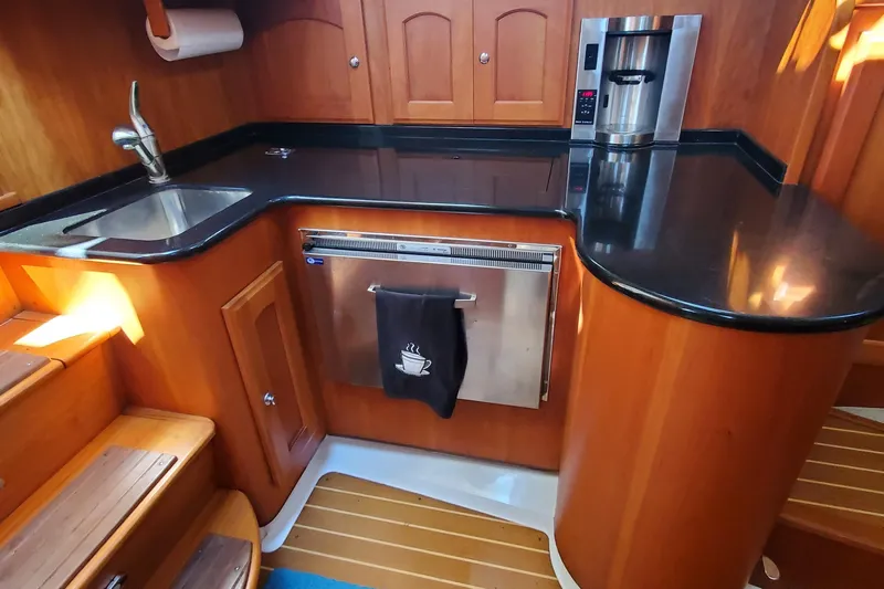 Puffin Yacht Photos Pics Compact kitchen in 2008 Legacy 32 boat with wood cabinetry and stainless steel appliances.