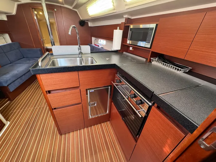 Dreamcatcher Yacht Photos Pics 2018 Hanse 348 yacht interior with modern kitchen, wood cabinetry, and striped flooring.