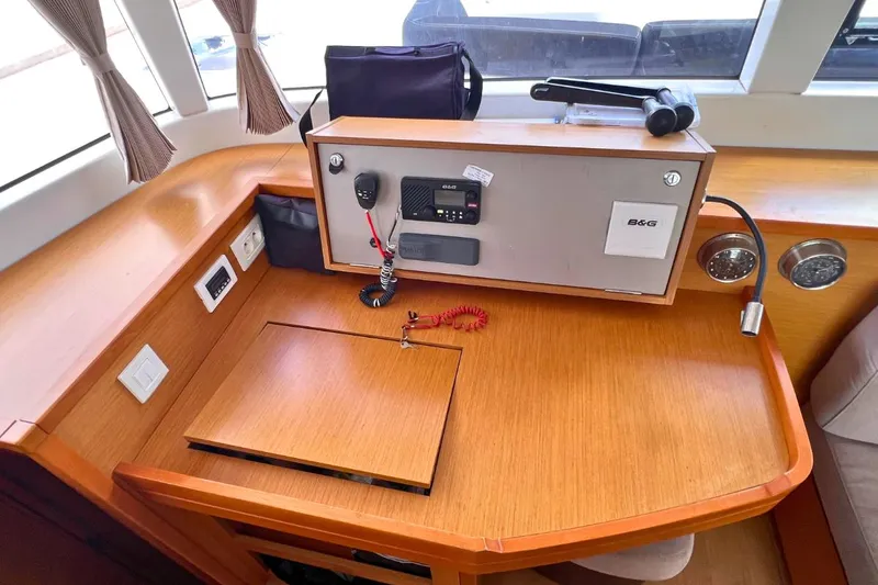 Take It Easy Yacht Photos Pics Navigation station of 2018 Lagoon 450 F catamaran with communication equipment and wooden desk.