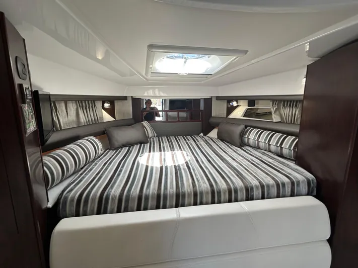 Aguabendita Yacht Photos Pics 2019 Monterey 345 Sport Yacht interior with striped bedding and skylight.