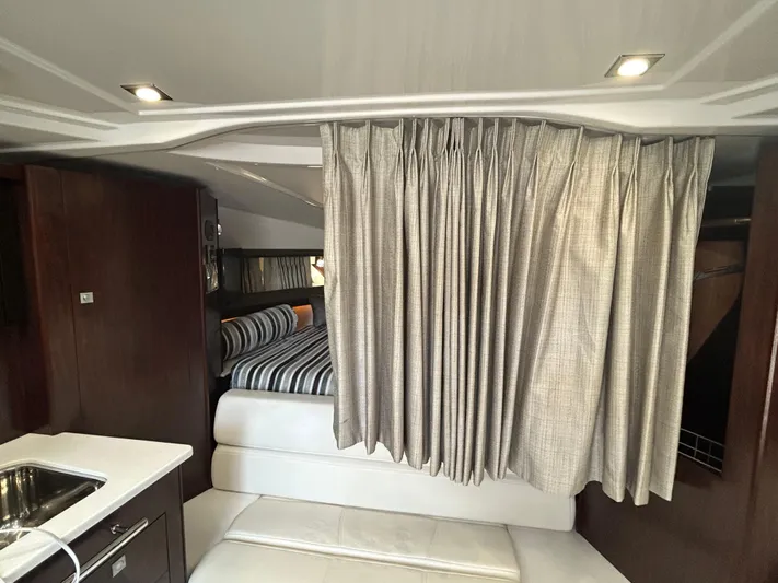 Aguabendita Yacht Photos Pics 2019 Monterey 345 Sport Yacht interior with bed, curtain, and kitchenette.