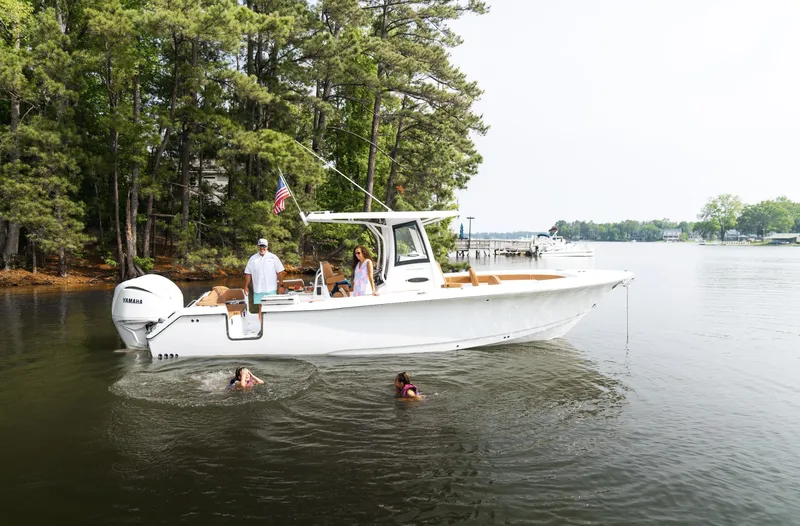  Yacht Photos Pics 2025 Sea Hunt Ultra 305 SE boat on a serene lake with swimmers nearby.