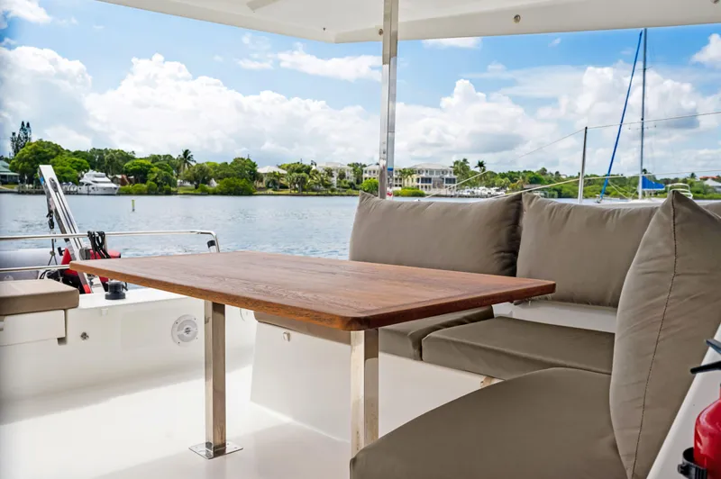 Sabai Sabai Yacht Photos Pics Fountaine Pajot Lucia 40 yacht, 2018 model, featuring a cozy outdoor seating area with a wooden table.