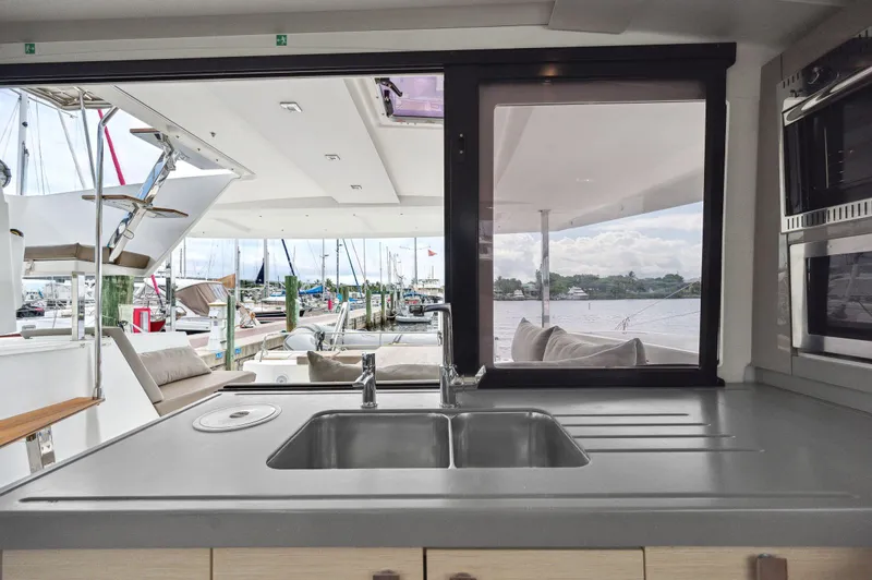 Sabai Sabai Yacht Photos Pics Interior view of 2018 Fountaine Pajot Lucia 40 catamaran kitchen with marina backdrop.