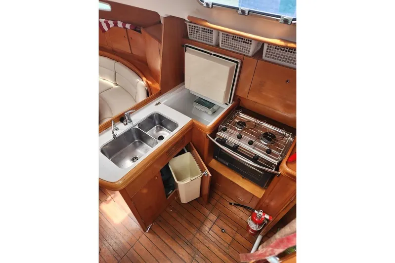  Yacht Photos Pics Interior of 2005 Beneteau First 44.7 yacht kitchen with sink, stove, and seating area.