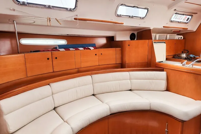  Yacht Photos Pics Interior of 2005 Beneteau First 44.7 yacht with curved seating and wooden cabinetry.