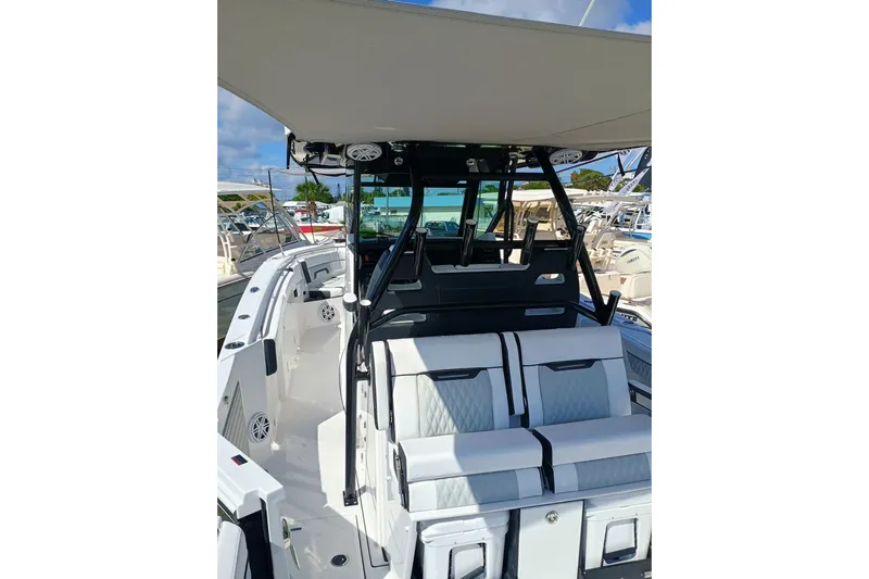 332-299 Yacht Photos Pics 2025 Blackfin 332 CC boat interior with seating and canopy, docked under clear skies.