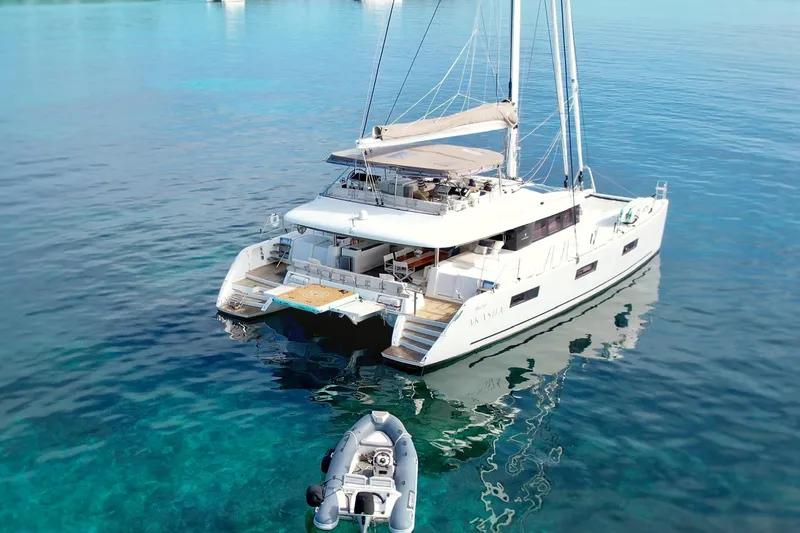  Yacht Photos Pics 2018 Lagoon 620 catamaran on clear blue water with a small dinghy nearby.