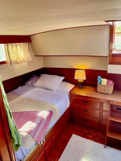 Padre Pio Yacht Photos Pics Cozy cabin interior of 1986 Grand Banks 42 Classic with bed, lamp, and wooden furnishings.