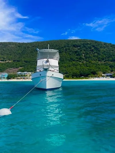 Padre Pio Yacht Photos Pics 1986 Grand Banks 42 Classic yacht anchored in clear blue water near a lush green shoreline.