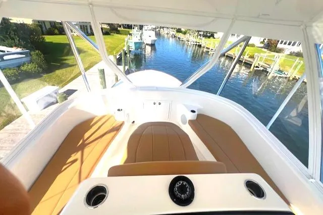  Yacht Photos Pics 2024 Custom Carolina Albemarle Spencer boat interior with tan seating, docked by a scenic canal.