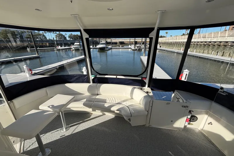 Liberty Call Yacht Photos Pics 2005 Cruisers Yachts 455 Express Motoryacht aft deck area with marina view, featuring seating, tables and Strataglass Enclosure.