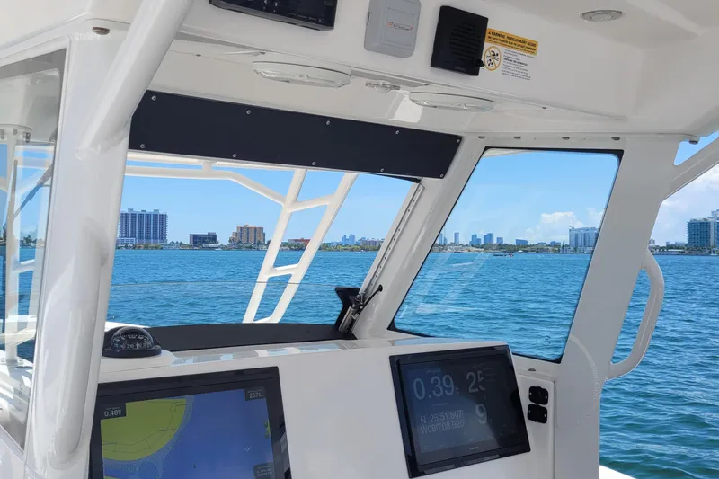  Yacht Photos Pics Interior view of 2018 Everglades 355 Center Console boat with navigation screens, overlooking city skyline.