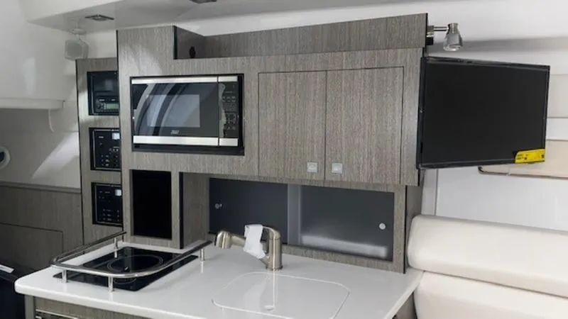  Yacht Photos Pics 2022 Monterey 295 Sport Yacht interior kitchen with microwave, stove, and TV.