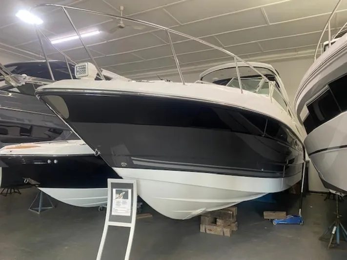  Yacht Photos Pics 2022 Monterey 295 Sport Yacht in showroom, sleek black and white design, elevated on blocks.