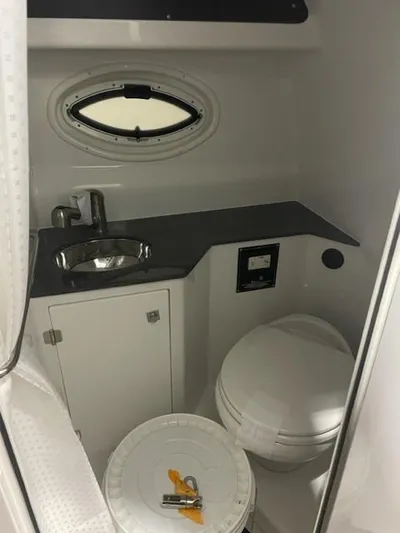  Yacht Photos Pics 2022 Monterey 295 Sport Yacht bathroom with sink, toilet, and porthole window.