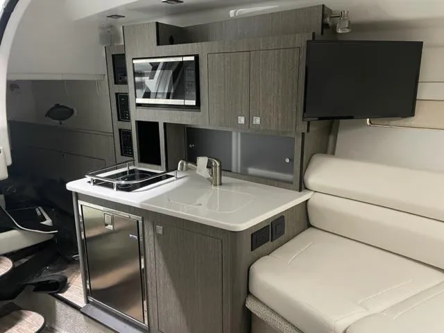  Yacht Photos Pics Interior of 2022 Monterey 295 Sport Yacht with kitchenette, sofa, and TV.