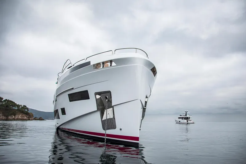  Yacht Photos Pics Luxury Sirena 88 yacht, 2023 model, anchored in serene waters under cloudy skies.
