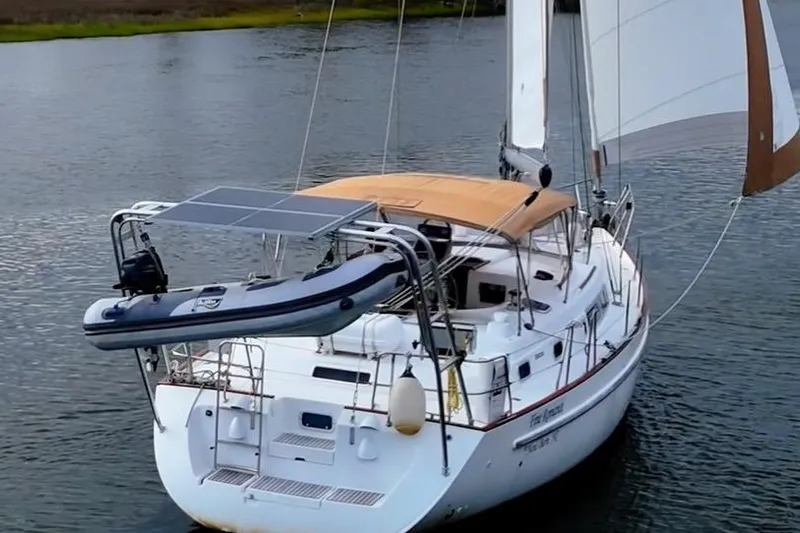 Fine Romance Yacht Photos Pics 1997 Beneteau Oceanis 40 CC sailboat with solar panels and dinghy on calm water.