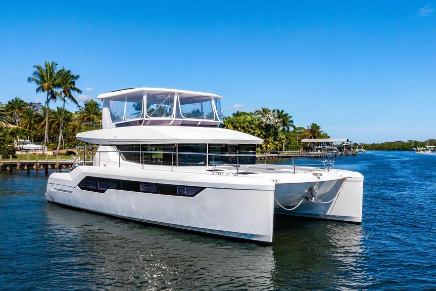 2022 Leopard 53 Powercat yacht cruising on a sunny day near palm-lined shore.