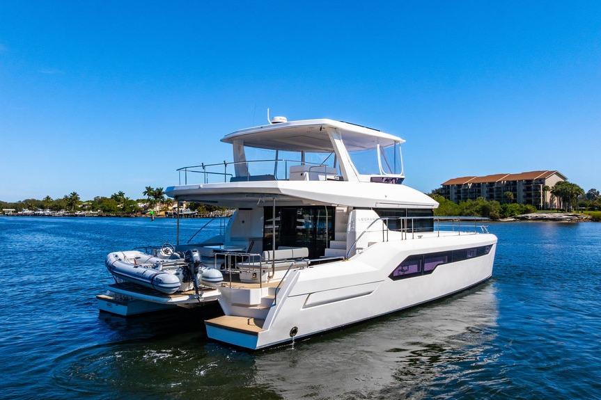 2022 Leopard 53 Powercat yacht cruising on a sunny day near coastal buildings.