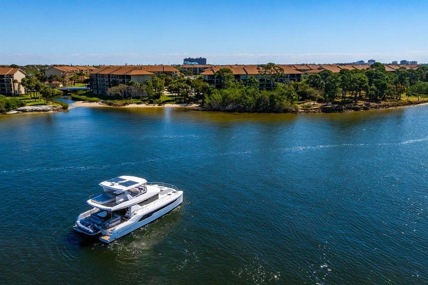 2022 Leopard 53 Powercat cruising on a scenic waterway near residential area.