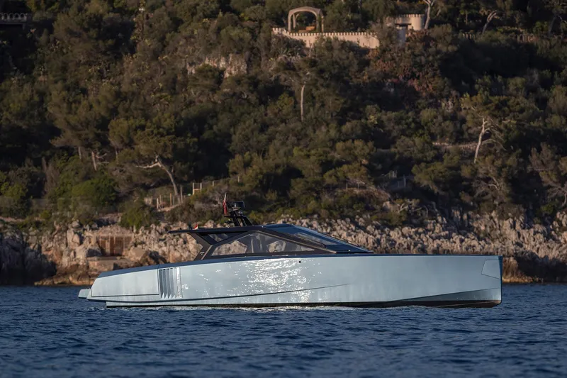  Yacht Photos Pics 2022 Wally WALLYPOWER58 yacht cruising near a rocky, forested coastline.