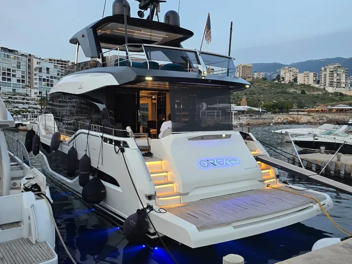  Yacht Photos Pics 2023 Cranchi Sessantasette 67 yacht docked at marina, illuminated with blue lights.