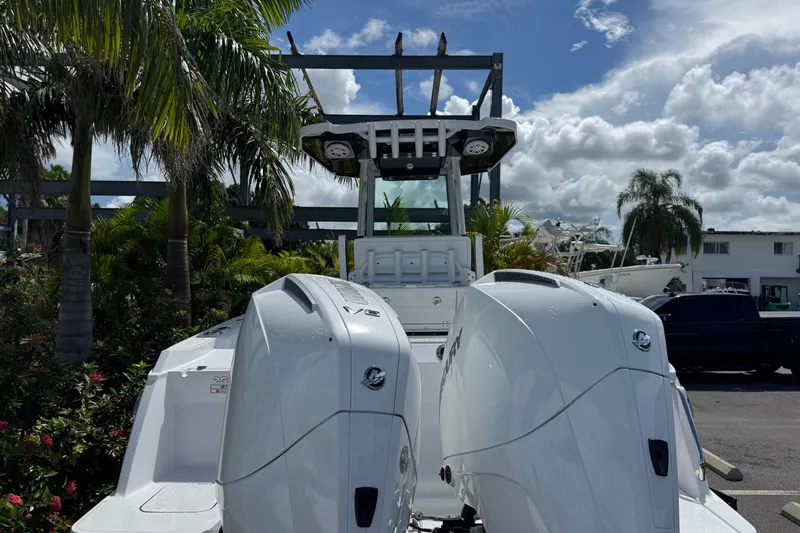 Yacht Photos Pics 2025 Blackfin 252 CC boat with dual outboard engines, surrounded by tropical foliage.