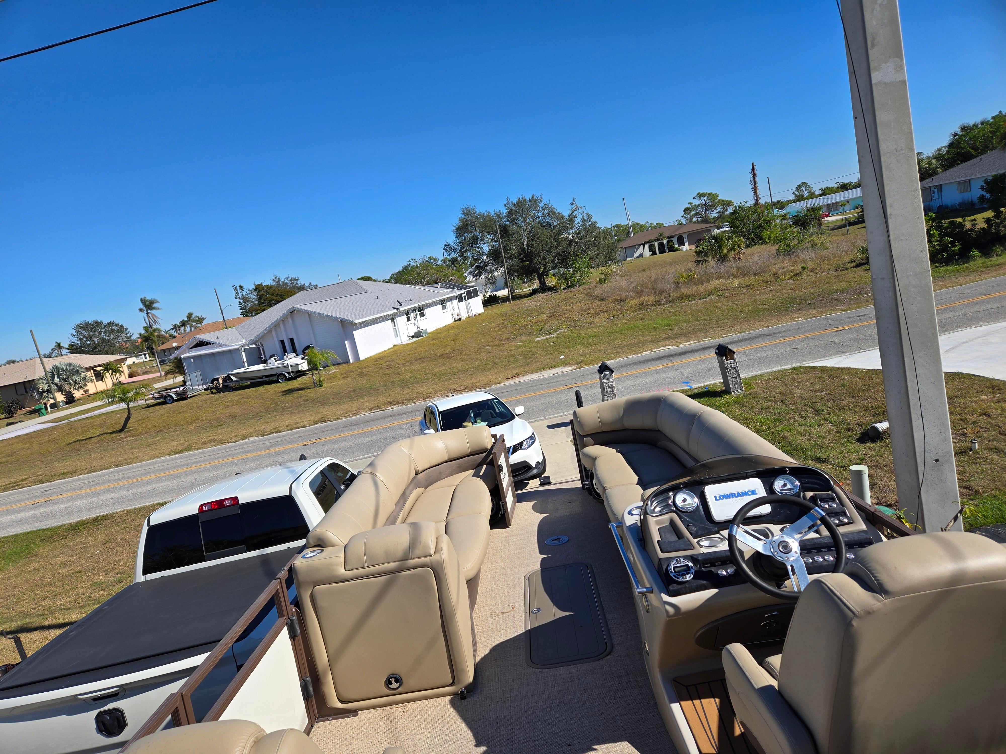 2017 Regency 254 LE3 pontoon boat with beige seating, parked near residential area.