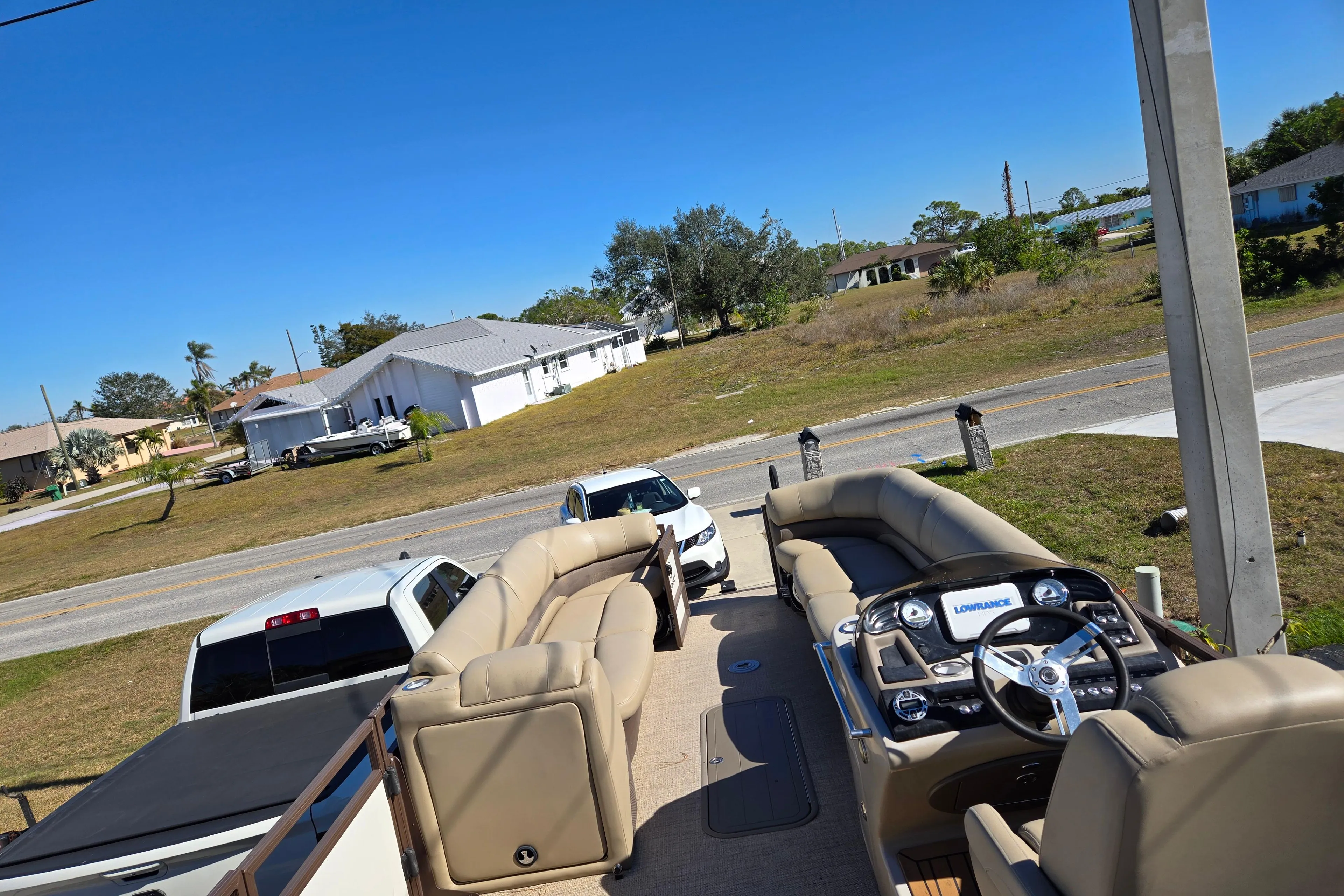 2017 Regency 254 LE3 pontoon boat with beige seating, parked near residential area.