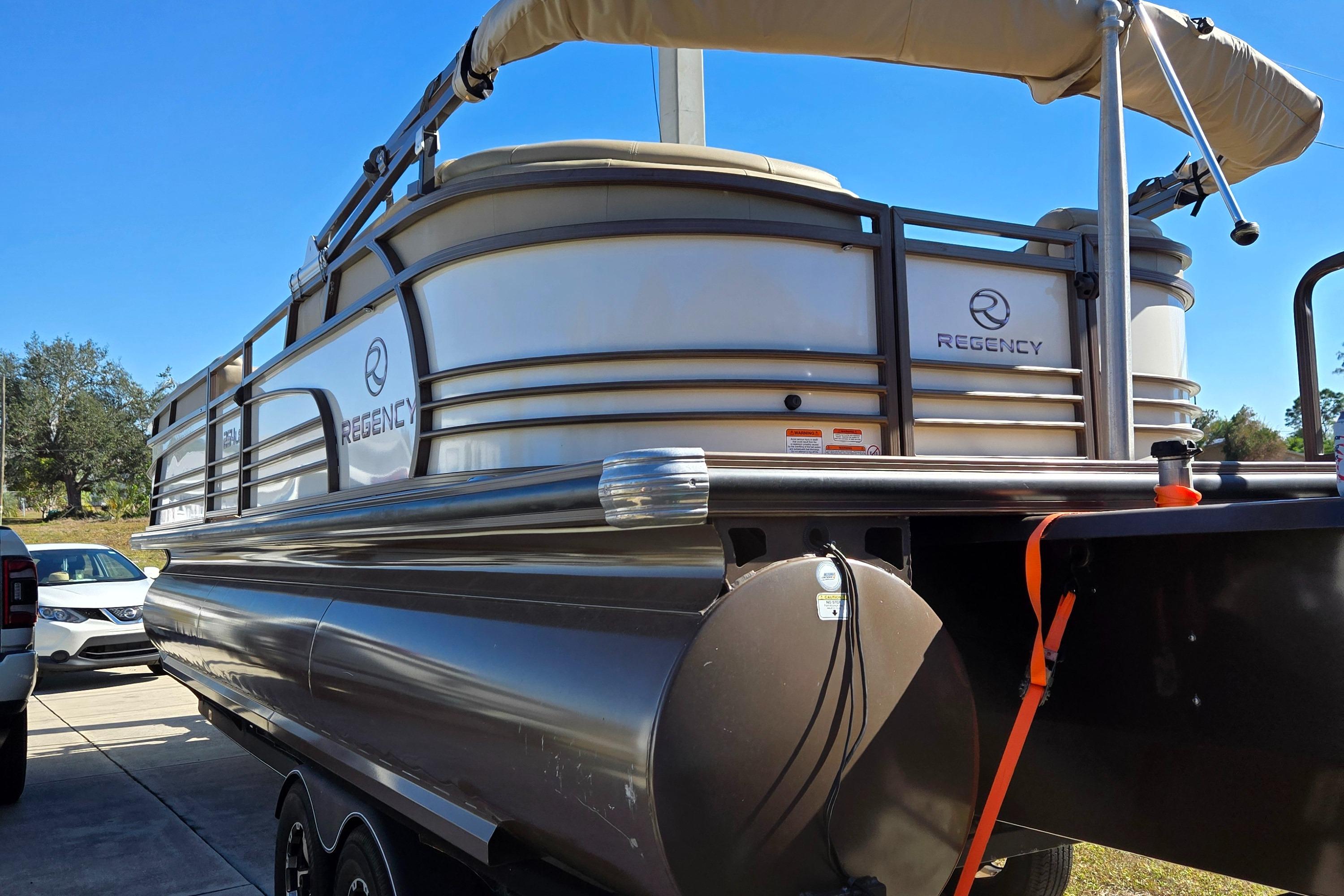 2017 Regency 254 LE3 pontoon boat parked on driveway, side view.