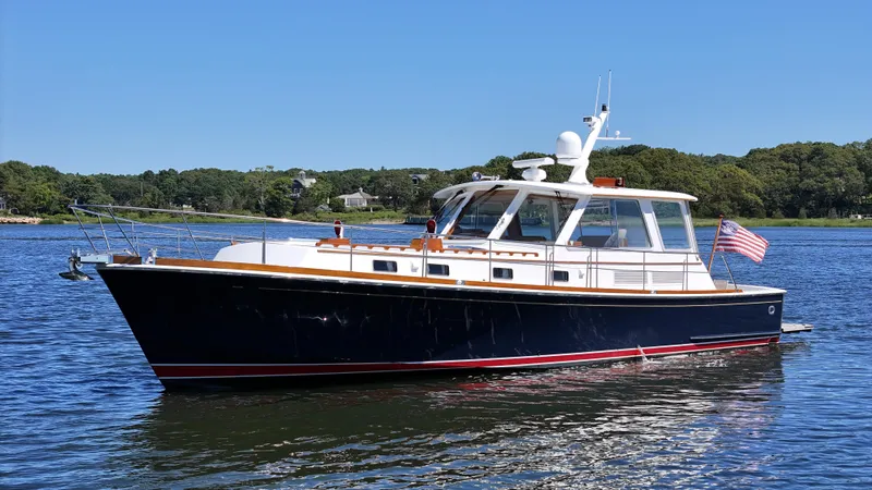 Ballena Yacht Photos Pics 2002 Grand Banks 49 Eastbay HX yacht on calm water, with American flag, under clear blue sky.